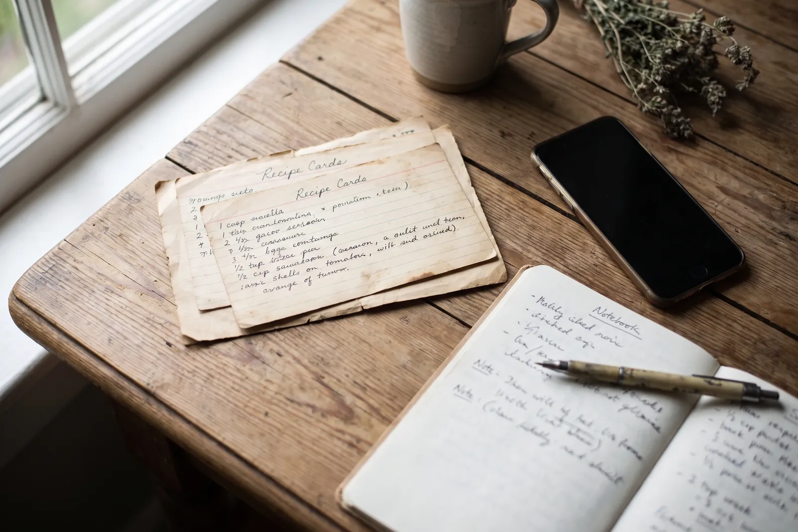 Handwritten recipe cards and a smartphone on a table, seen from above